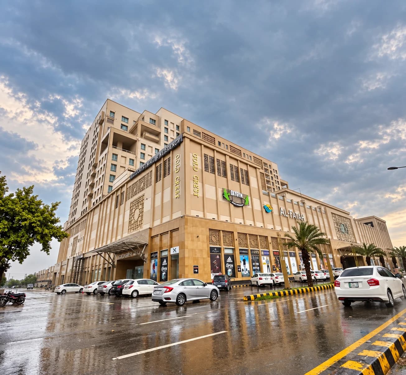 Goldcrest Mall & Residency in DHA Phase 4, Lahore, with its sandstone facade reflected on the rain-wet street