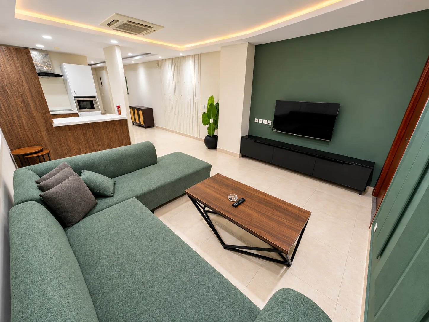 Lounge with a green L-shaped sofa, television and wooden coffee table